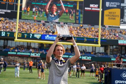 Noah Johnson holding the Madden trophy at a WVU Football game.